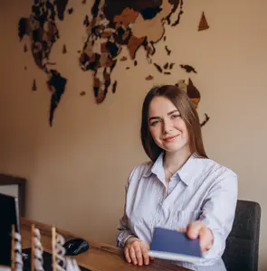 A woman smiling while holding her passport in an office, symbolizing the excitement of completing the visa application and preparing for a trip.